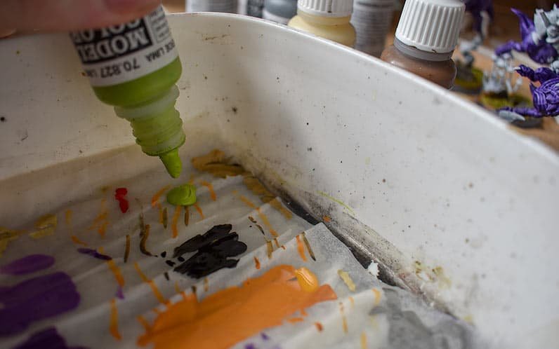 A picture showing a vallejo green dropping a drop of paint onto the palette