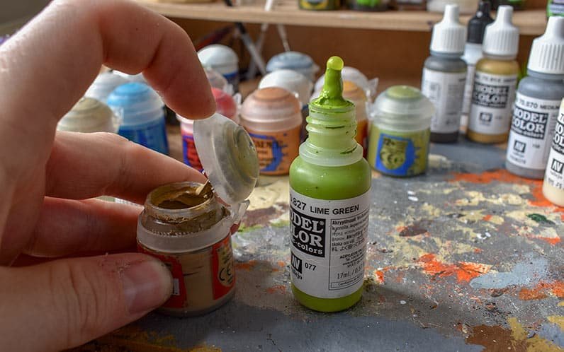 An image of vallejo dropper bottle side by side with a citadel paint pot showing the dryed paint in the lid