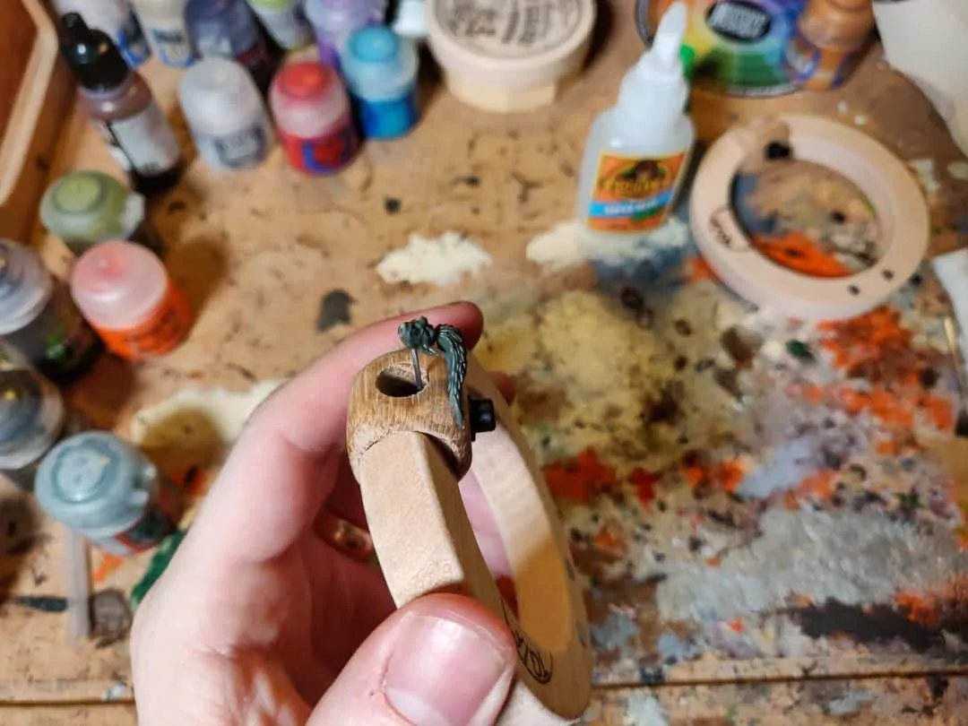 Showing the head and how it is attached to a small piece of metal (a paper clip) while painting a miniature face