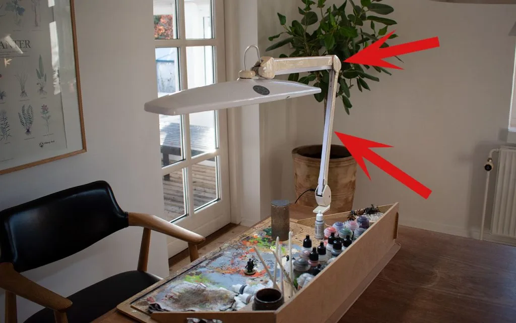 A normal LED task lamp will have stiff parts joined together with some sort of turnable element. This makes it harder to get into the right position and it can sag if the construction is poor. This image show a lamp with red arrows painting at those elements.